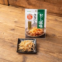 おいしい減塩さきいかのパッケージと皿に盛られたさきいか。木目のカウンター。